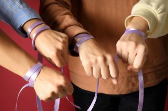 mains de femmes tenant un ruban violet, photo d'illustration pour la lutte contre les violences faites aux femmes